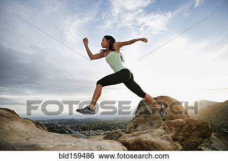 Stock Photograph - Vietnamese woman leaping on rocky hillside. Fotosearch