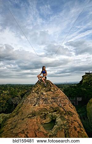 Stock Image - Vietnamese woman sitting on rocky hilltop. Fotosearch