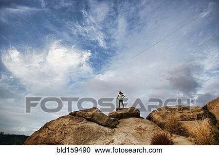 Stock Image - Vietnamese woman standing on rocky hilltop. Fotosearch