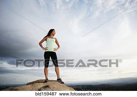 Stock Photo - Vietnamese woman standing on rocky hilltop. Fotosearch