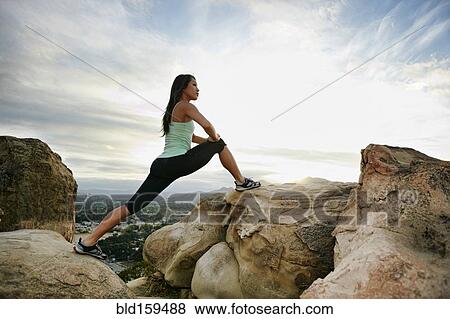 Stock Photo - Vietnamese woman stretching on rocky hilltop. Fotosearch