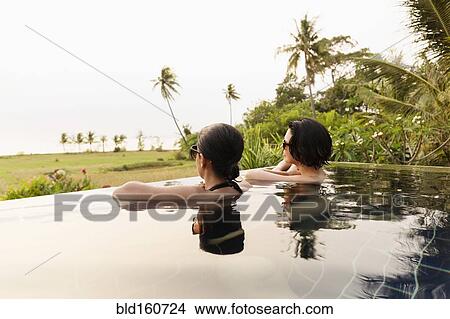 Picture - Women admiring scenic view in infinity pool. Fotosearch