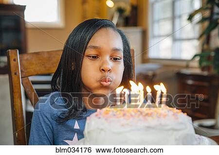 Black Girl Blowing Out Candles On Birthday Cake Stock Photograph Blm Fotosearch