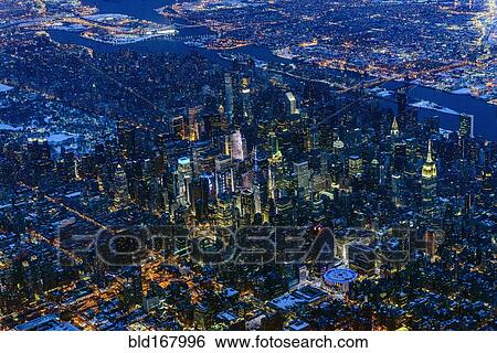 Stock Photograph - Aerial view of Manhattan cityscape and river at night, New York, United States. Fotosearch
