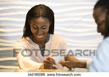 Stock Photograph - African American concierge checking guest into hotel. Fotosearch