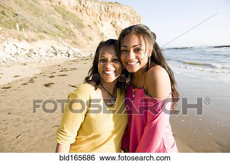 Stock Photograph - African American mother and daughter smiling on beach. Fotosearch