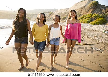 Stock Image - African American mother and daughters walking on beach. Fotosearch