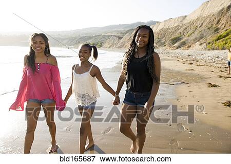 Stock Photo - African American sisters holding hands on beach. Fotosearch
