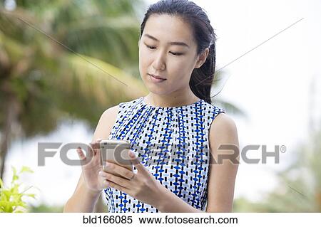 Stock Photography - Asian businesswoman using cell phone outdoors. Fotosearch