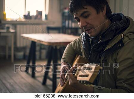 Asian man playing guitar in living room View Large Photo Image Stock Photo - Asian man playing guitar in living room. Fotosearch