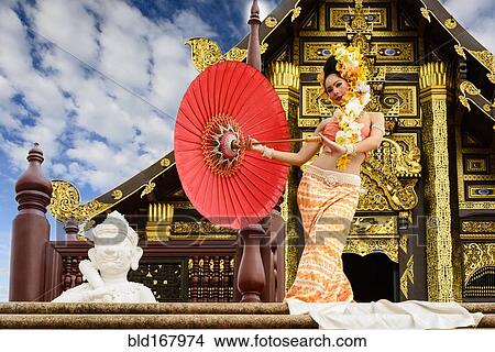 Picture - Asian woman with parasol on stairs of ornate Buddhist temple, Chiang Mai, Chiang Mai, Thailand. Fotosearch