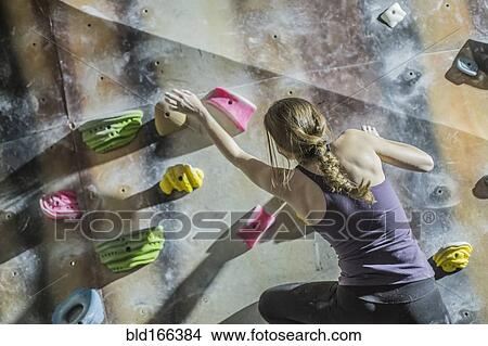 Picture - Athlete climbing rock wall in gym. Fotosearch
