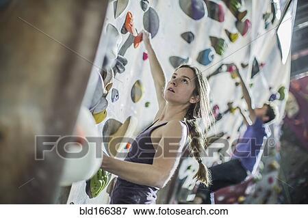 Stock Photo - Athlete climbing rock wall in gym. Fotosearch