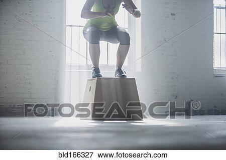 Stock Photo - Athlete crouching on platform in gym. Fotosearch