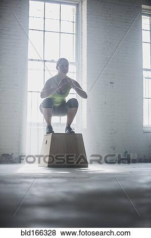 Stock Photo - Athlete crouching on platform in gym. Fotosearch