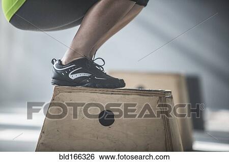 Stock Photograph - Athlete crouching on platform in gym. Fotosearch