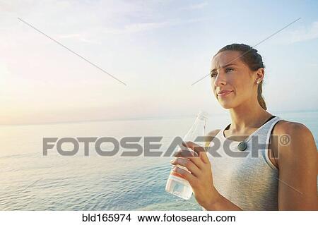 Athlete drinking water bottle on beach View Large Photo Image Picture - Athlete drinking water bottle on beach. Fotosearch