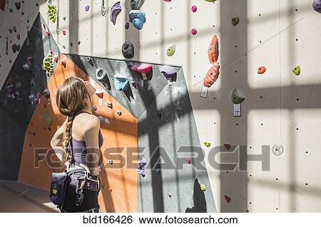 Athlete examining rock wall in gym View Large Photo Image Stock Photograph - Athlete examining rock wall in gym. Fotosearch
