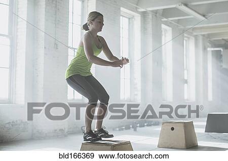Stock Photo - Athlete jumping on platform in gym. Fotosearch