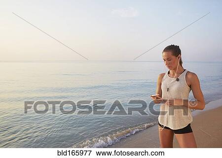 Stock Photo - Athlete listening to earphones on beach. Fotosearch