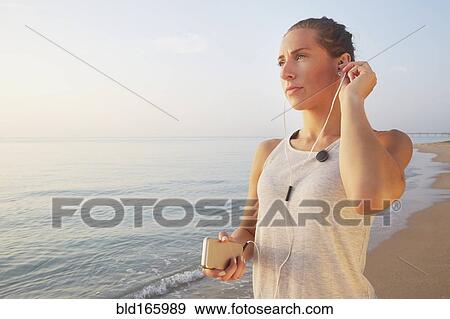 Athlete listening to earphones on beach View Large Photo Image Stock Photo - Athlete listening to earphones on beach. Fotosearch
