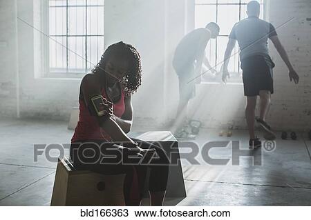 Stock Image - Athlete listening to mp3 player in gym. Fotosearch