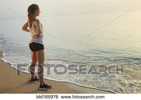 Stock Photograph - Athlete overlooking ocean on beach. Fotosearch