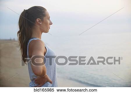 Stock Photography - Athlete overlooking ocean on beach. Fotosearch