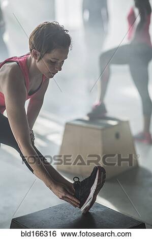 Stock Photograph - Athlete stretching leg in gym. Fotosearch