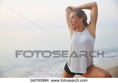 Picture - Athlete stretching on beach. Fotosearch
