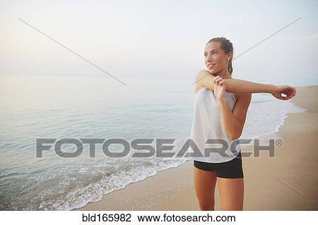Stock Image - Athlete stretching on beach. Fotosearch
