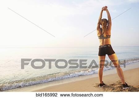 Stock Image - Athlete stretching on beach. Fotosearch