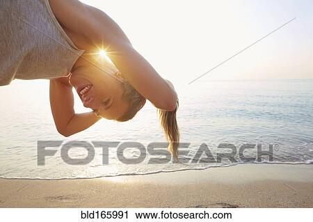 Stock Image - Athlete tying hair in ponytail on beach. Fotosearch