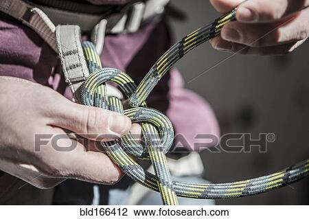 Stock Image - Athlete tying knot on climbing harness. Fotosearch