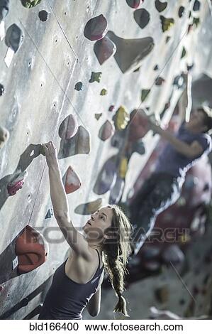 Athletes climbing rock wall in gym View Large Photo Image Stock Image - Athletes climbing rock wall in gym. Fotosearch