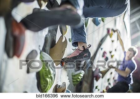 Stock Photograph - Athletes climbing rock wall in gym. Fotosearch
