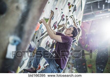 Athletes climbing rock wall in gym View Large Photo Image Stock Photography - Athletes climbing rock wall in gym. Fotosearch