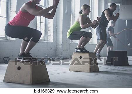 Stock Photo - Athletes crouching on platforms in gym. Fotosearch