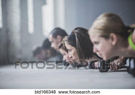 Athletes doing push-ups and lifting weights on floor View Large Photo Image Stock Photo - Athletes doing push-ups and lifting weights on floor. Fotosearch