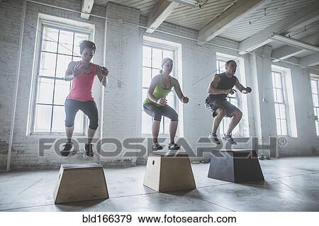 Stock Photo - Athletes jumping on platforms in gym. Fotosearch