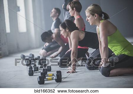 Stock Image - Athletes resting on floor near dumbbells. Fotosearch