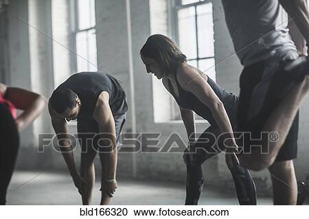 Stock Image - Athletes stretching legs in gym. Fotosearch