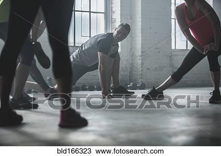 Athletes stretching legs in gym View Large Photo Image Stock Image - Athletes stretching legs in gym. Fotosearch