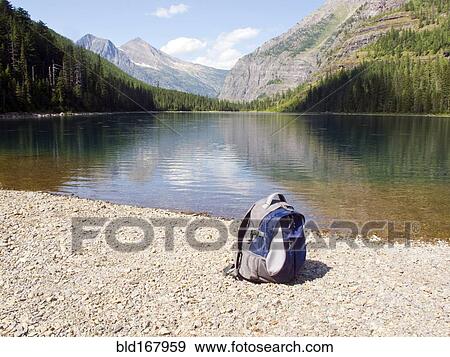 Stock Photo - Backpack at mountain lake, Glacier National Park, Montana, United States. Fotosearch