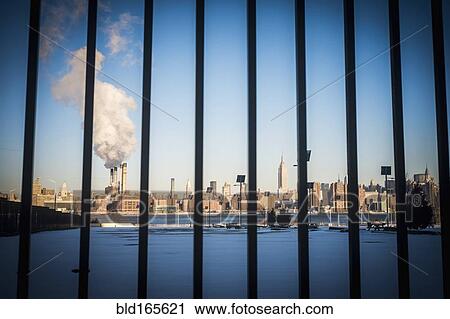 Stock Image - Bars in front of smokestack in city skyline, New York, New York, United States. Fotosearch