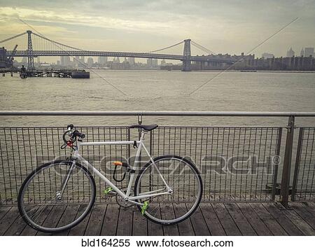 Bicycle locked to waterfront railing overlooking urban bridge, New York, New York, United States View Large Photo Image Stock Photography - Bicycle locked to waterfront railing overlooking urban bridge, New York, New York, United States. Fotosearch