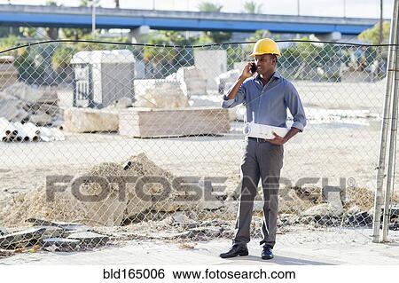 Black architect in hard hat talking on cell phone View Large Photo Image Stock Photograph - Black architect in hard hat talking on cell phone. Fotosearch