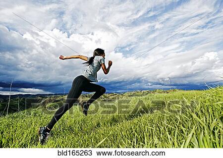 Stock Image - Black athlete running on rural hilltop. Fotosearch