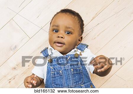 Stock Image - Black baby boy laying on floor. Fotosearch