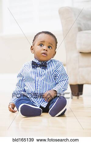 Stock Photo - Black baby boy sitting on living room floor. Fotosearch